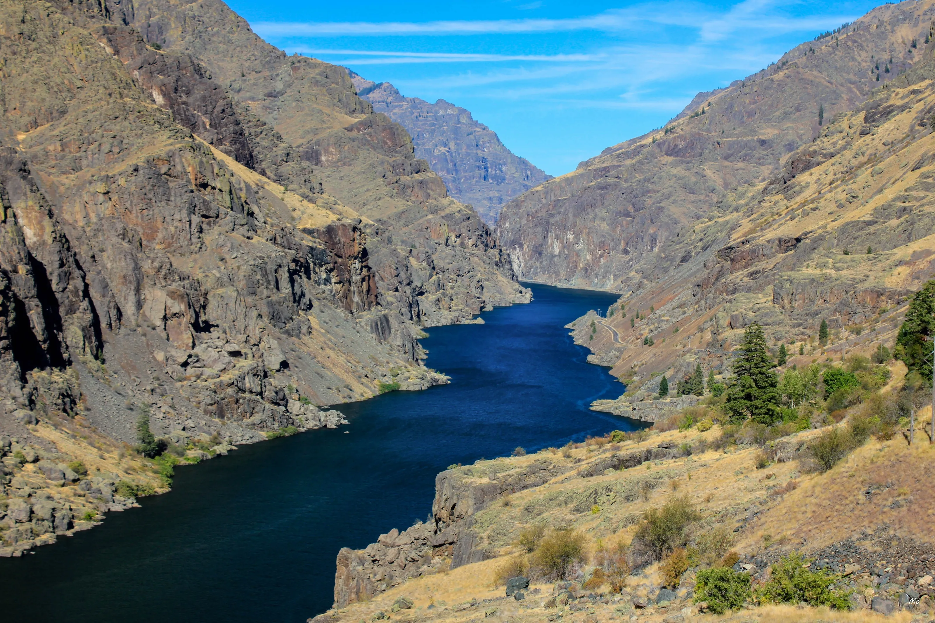 A deep river canyon with steep brown walls under a blue sky