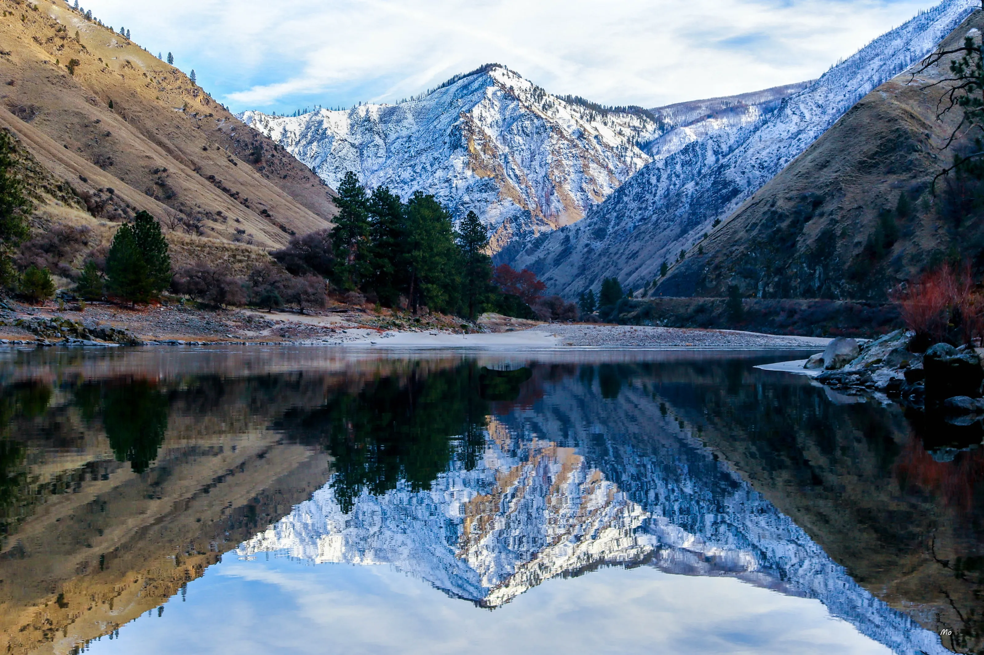 Snow-dusted peaks reflected in a still river